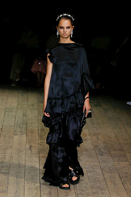 Desfile Simone Rocha na LFW Primavera / Verão 20, modelo usa vestido longo em cetim preto.