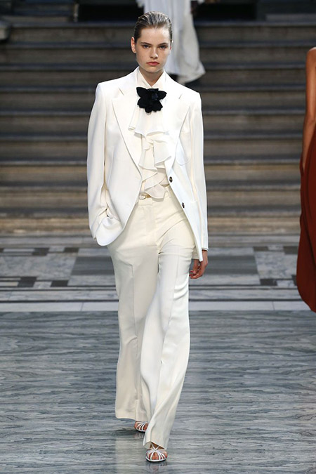Desfile Victoria Beckham na LFW Primavera / Verão 20, modelo veste terno branco com camisa bufante branca e gravata em laço preta.