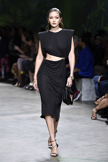 No desfile da Versace da MFW Primavera / Verão 20, Gigi Hadid veste vestido preto com recorte na cintura.