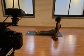Mulher faz posição de yoga em frente à câmeras de vídeo