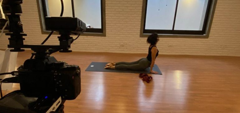 Mulher faz posição de yoga em frente à câmeras de vídeo