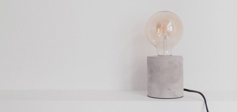 Lâmpada em luminária de concreto, desligada, faz pensar em como economizar na conta de luz