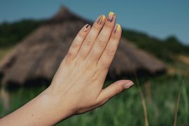 mão de uma mulher de unhas pintadas no campo