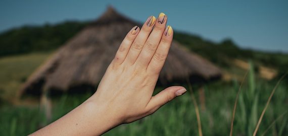mão de uma mulher de unhas pintadas no campo