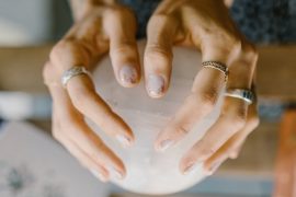 ma~e de mulher branca com aneis segurando uma bola de cristal